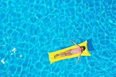 Yüzme havuzunda şişme yataktaki kız, üst manzara. Yaz tatili