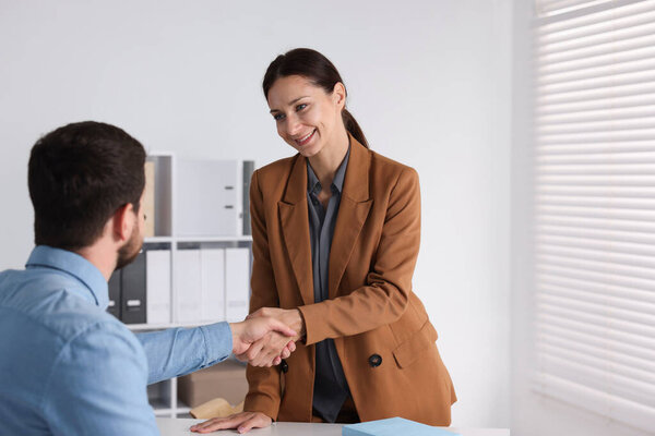 Деловые партнеры пожимают друг другу руки за столом в помещении, пространство для текста