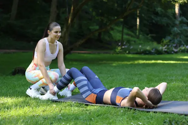 Dışarıda profesyonel antrenörle egzersiz yapan genç bir kadın.