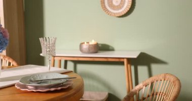 Yemek odasındaki ahşap masada, tabak ve vazo çiçekli şık bir ortam, sola hareket eden bir kamera. İç tasarım