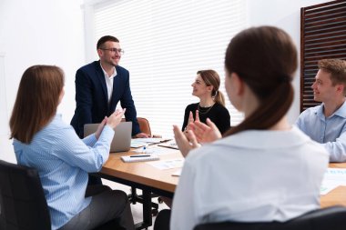 Ofisteki bir grup insanla çalışan bir iş koçu.