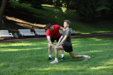 Genç adam profesyonel antrenörle dışarıda egzersiz yapıyor.