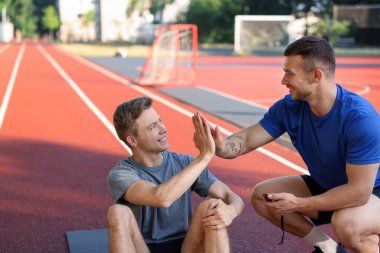 Profesyonel kişisel antrenörü olan genç adam dışarıda beşlik çakıyor.