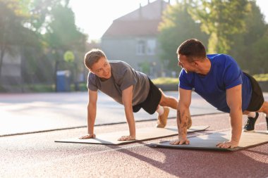 Genç adam profesyonel antrenörle dışarıda egzersiz yapıyor.