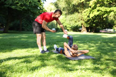 Dışarıda profesyonel antrenörle egzersiz yapan genç bir kadın.