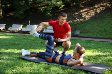Dışarıda profesyonel antrenörle egzersiz yapan genç bir kadın.