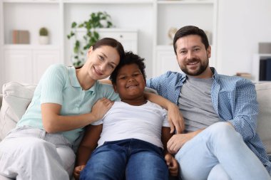 Evlat edinme. Mutlu ebeveynler ve oğulları evde.