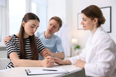 Tüp bebek (tüp bebek). Üreme kliniğine yaptığı ziyarette üzgün çifti destekleyen doktor