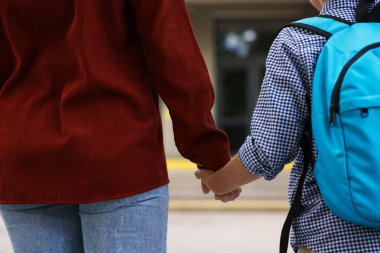 Anne oğluyla el ele tutuşup onu okula götürüyor.