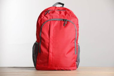 Ahşap masanın üzerinde kırmızı sırt çantası var.