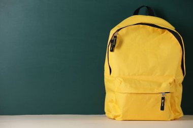 Tahtanın yanındaki masada sarı sırt çantası. Metin için boşluk