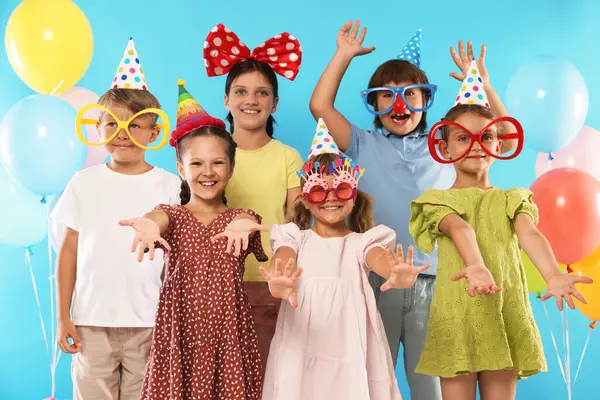 Doğum günü kutlaması. Açık mavi arka planda neşeli dekoru olan mutlu çocuklar.