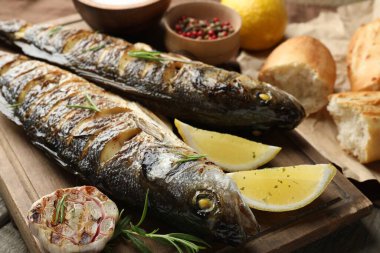 Ahşap masada, ekmek, biberiye ve limonla servis edilen lezzetli kavrulmuş deniz kabuğu balığı. Ev yapımı deniz ürünleri yemeği.