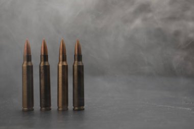 Gri masadaki ateşli silah fişekleri dumana karşı, yakın plan. Metin için boşluk