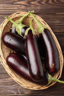 Tahta masada, sepetin içinde bir sürü olgun patlıcan var.