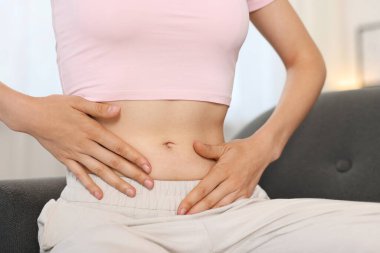 Evdeki kanepede göbekli bir kadın, yakın plan.