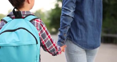 Anne kızıyla el ele tutuşuyor ve onu okula götürüyor.