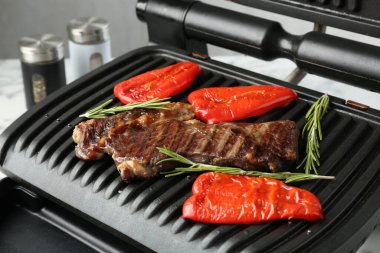 Biftekli ızgara, dolmalık biber ve biberiye beyaz masada, yakın plan.