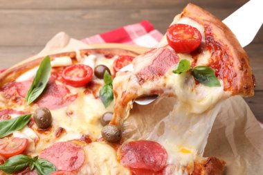 Peynirli, salamlı, domatesli ve zeytinli leziz pizzayı yakın plan.