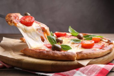 Peynirli, salamlı, domatesli ve zeytinli leziz pizzayı yakın plan.