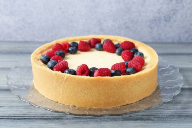Gri ahşap masada taze böğürtlenli lezzetli cheesecake, yakın plan.
