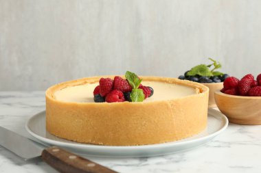 Taze böğürtlenli leziz cheesecake ve beyaz mermer masada bıçak, yakın plan.