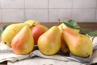 Açık gri kiremitli duvara karşı ahşap masada birçok taze armut, yakın plan.