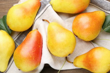 Bir sürü taze armut ve yeşil yapraklar ve ahşap masa üzerinde peçete, düz yatıyordu.