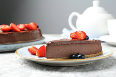 Açık gri desenli masada böğürtlenli çikolatalı cheesecake, yakın plan.