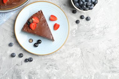 Açık gri desenli masada böğürtlenli çikolatalı cheesecake. Metin için boşluk