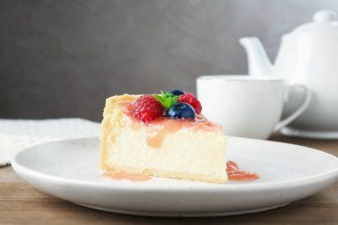 Ahşap masada böğürtlenli ve soslu lezzetli bir cheesecake.