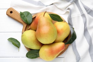 Taze armutlar ve yeşil yapraklar beyaz ahşap masada, düz yatıyordu.