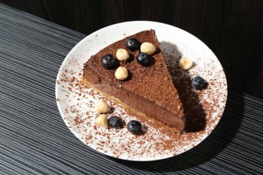 Üzerinde fındık ve yaban mersini olan lezzetli çikolatalı cheesecake.