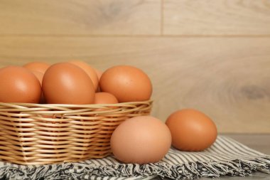 Hasır sepetteki çiğ tavuk yumurtaları ahşap tezgahın üstünde, yakın plan. Metin için boşluk