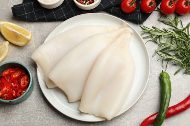 Çiğ kalamar parçaları, baharatlar ve ürünler gri desenli masa, düz yatıyordu.