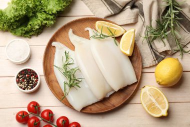 Hafif ahşap masa üzerinde ürünleri ve baharatları olan çiğ mürekkep balıkları.