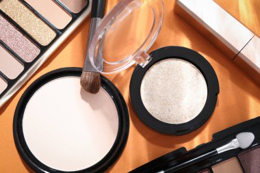 Renkli göz falı paletleri, turuncu arka planda toz ve makyaj fırçası, düz yatış