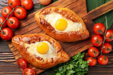 Peynirli, yumurtalı ve ahşap masadaki diğer ürünlerle nefis bir khachapuri.