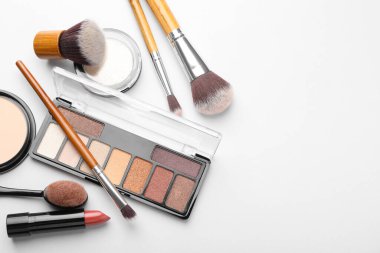 Göz falı paleti, diğer kozmetik ürünler ve beyaz arka planda fırçalar, düz zemin. Metin için boşluk