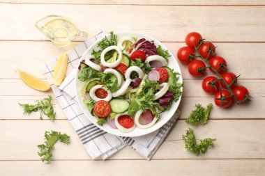 Delicious salad with squid rings and vegetables served on light wooden table, flat lay