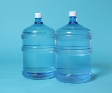 Açık mavi zemin üzerinde su olan soğutucu şişeler.