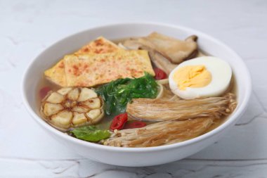 Beyaz masadaki eryngii mantarlı, enoki ve kral istiridyeli lezzetli ramen.