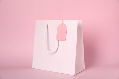 Pembe arka planda boş etiketli alışveriş çantası.