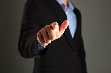 Adam gri arkaplanda bir şeye dokunuyor, yakın plan.