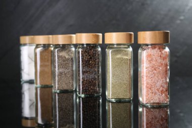 Farklı baharatlar cam kavanozlarda ayna yüzeyinde, yakın plan