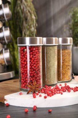 Gri ahşap masada farklı baharatlar ve cam kavanozlar, yakın plan.