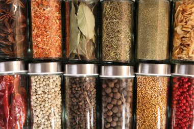 Different spices in glass jars as background, top view