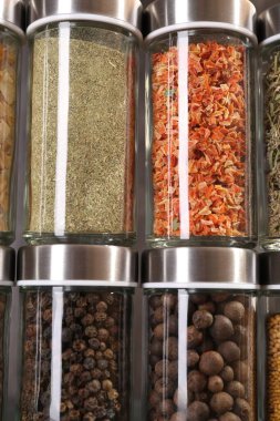Cam kavanozlardaki farklı baharatlar gri arka planda, yakın plan
