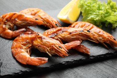 Siyah masada limonlu ve marullu ızgara karides, yakın plan. Lezzetli deniz ürünleri yemeği.