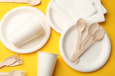 Sarı arkaplanda tek kullanımlık sofra takımı, düz konum
